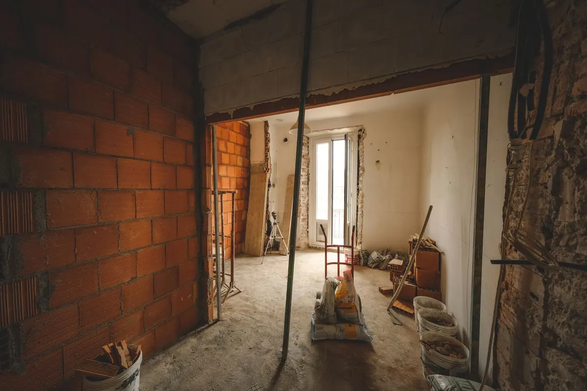Un locale al grezzo, con muri in mattoni e materiali di cantiere